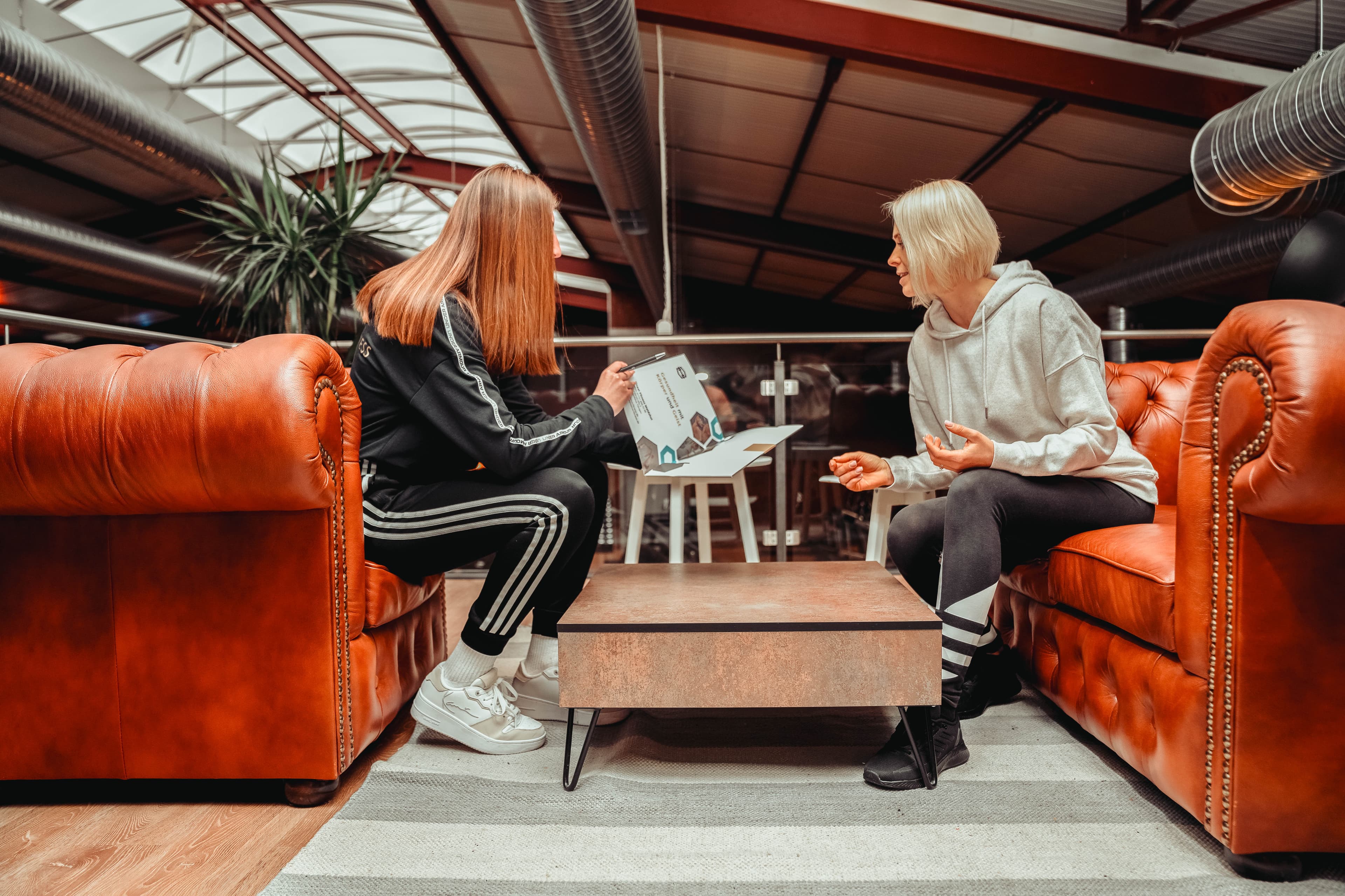 Two people sitting on a leather couch talking